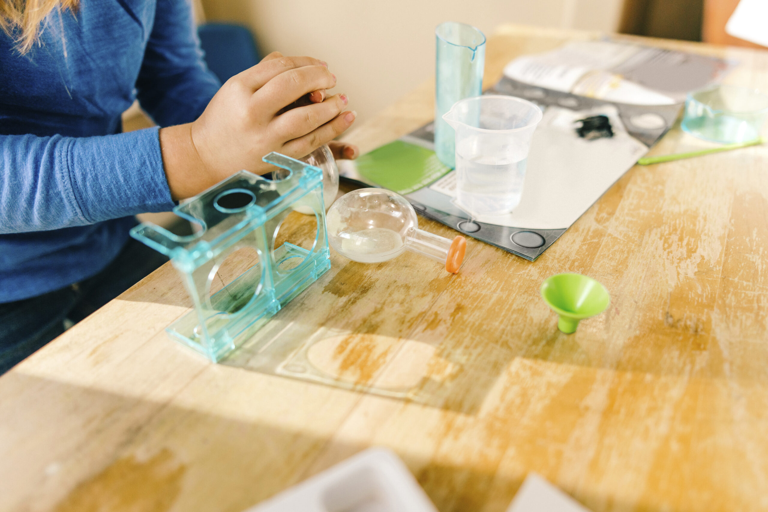 Student preparing to do a science experiment with plastic beakers and a funnel.