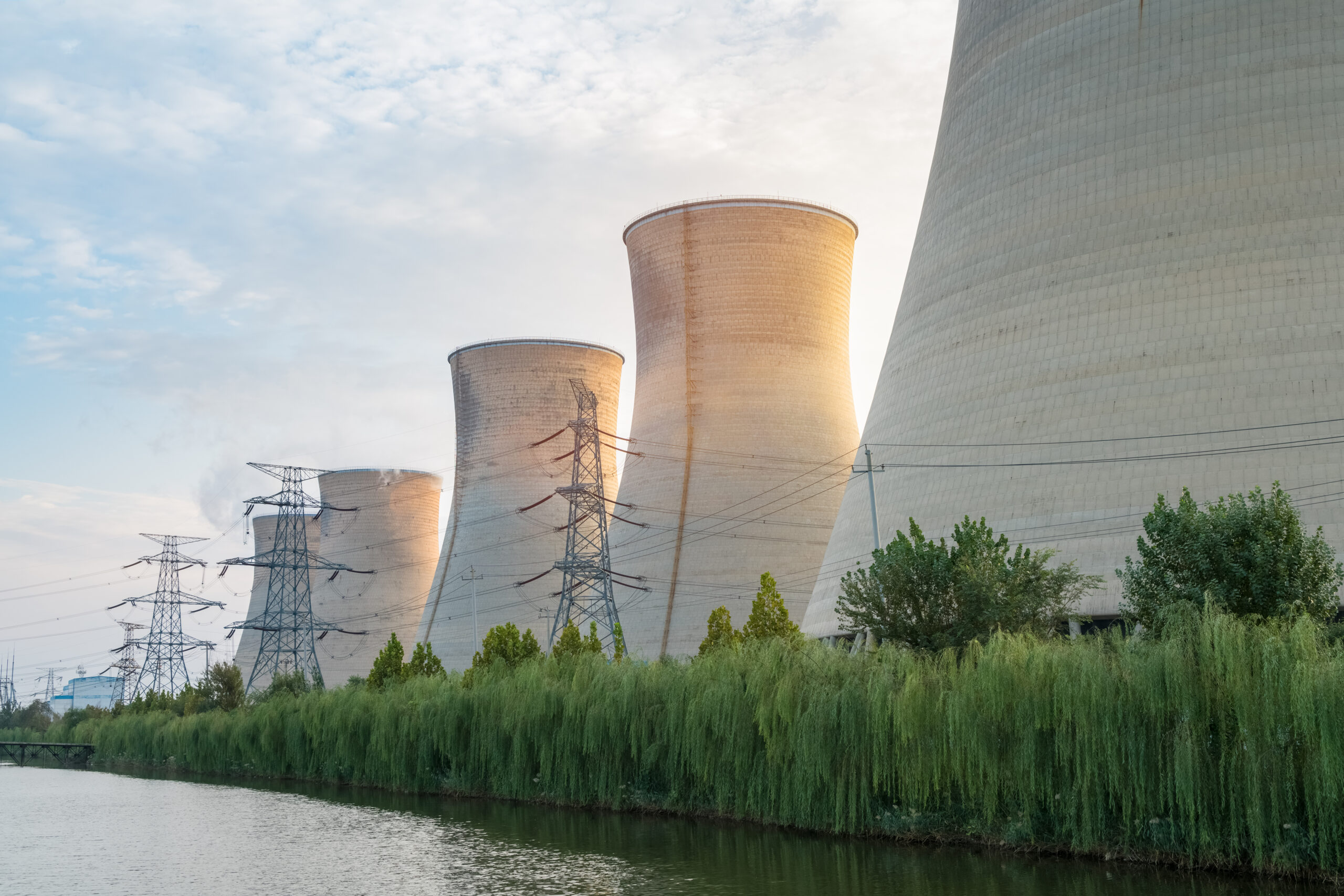 Cooling towers and transmission lines at a power plant beside a river.