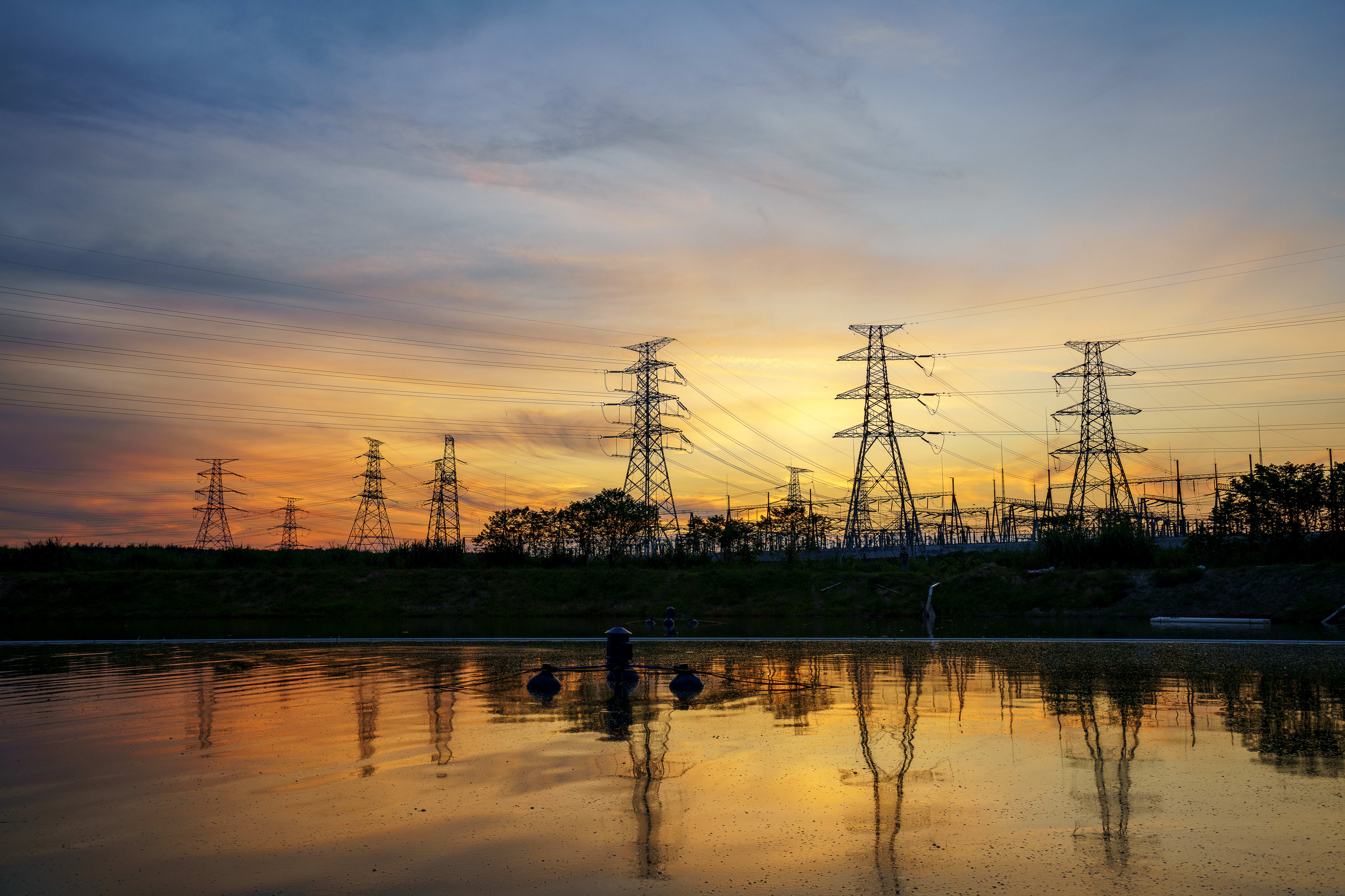 electricity transmission pylon silhouetted against blue sky at dusk