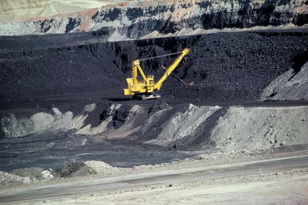 Large yellow excavator operating in an open-pit coal mine