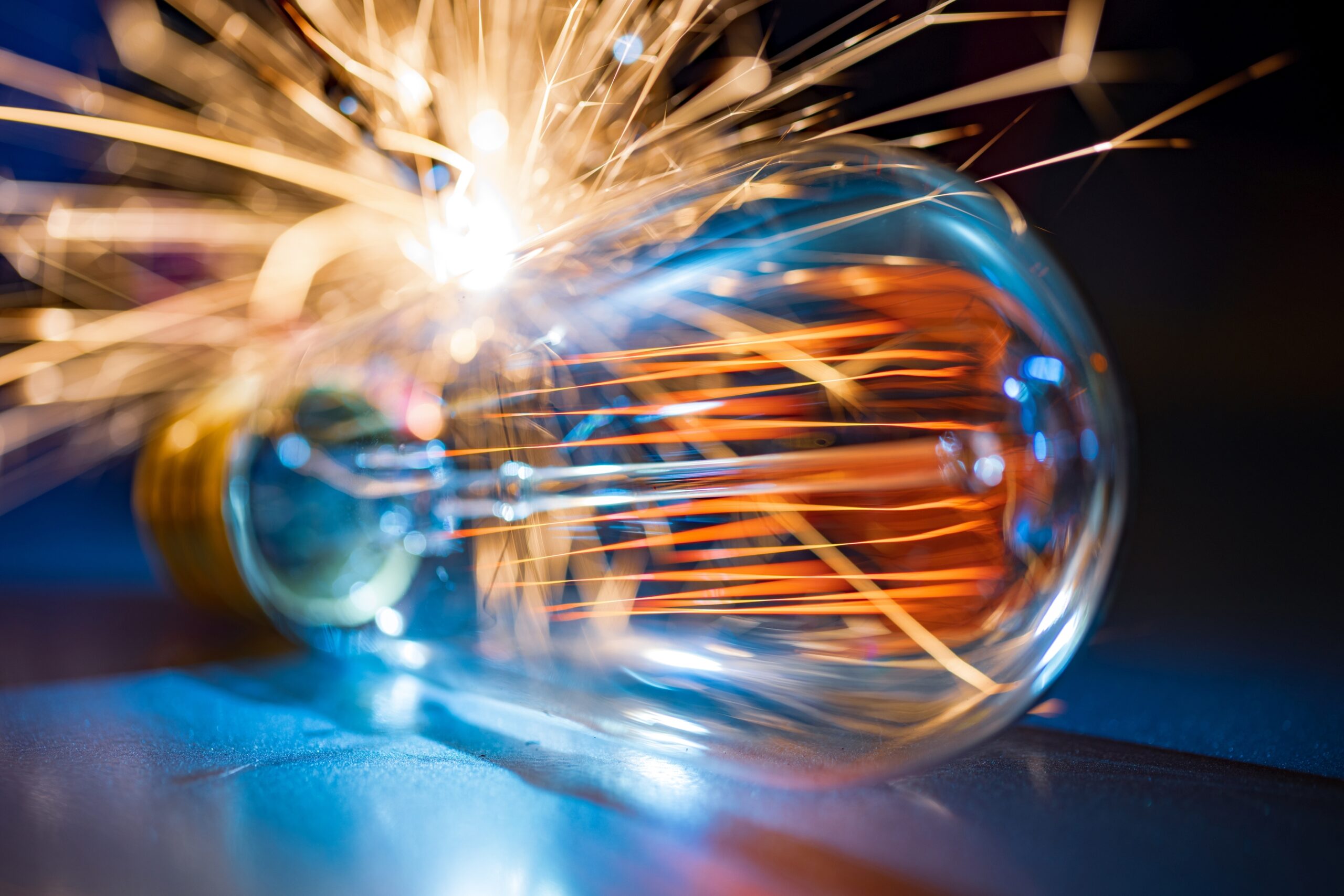 An old transparent glass incandescent lamp does not shine very brightly with an amber fiery light and quickly and sharply pour