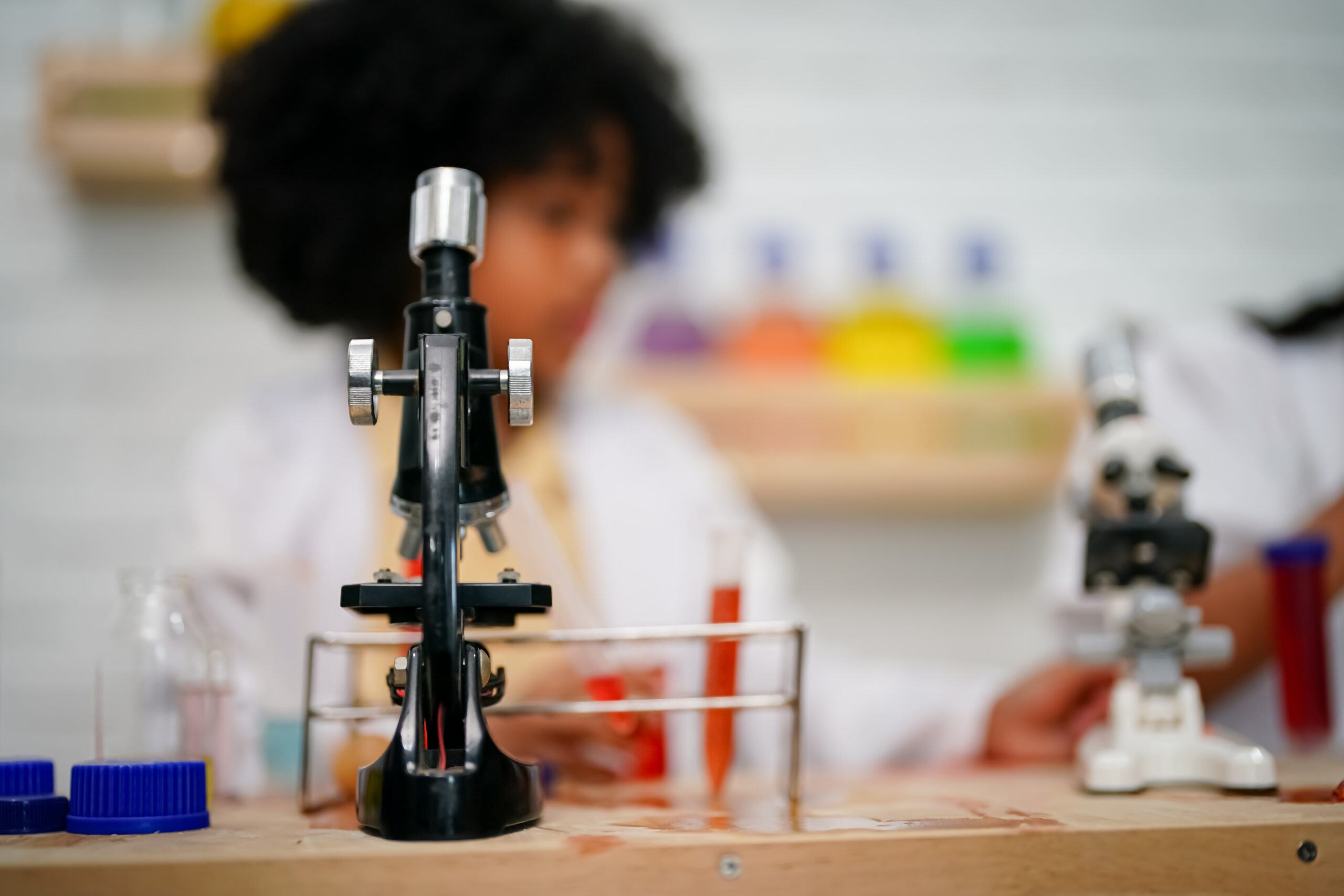 Young kid in a classroom blurred behind a microscope