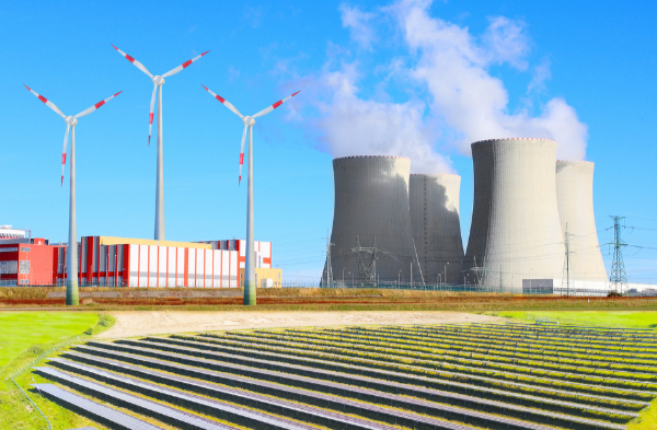 Energy facility with wind turbines, solar panels, and cooling towers emitting steam.