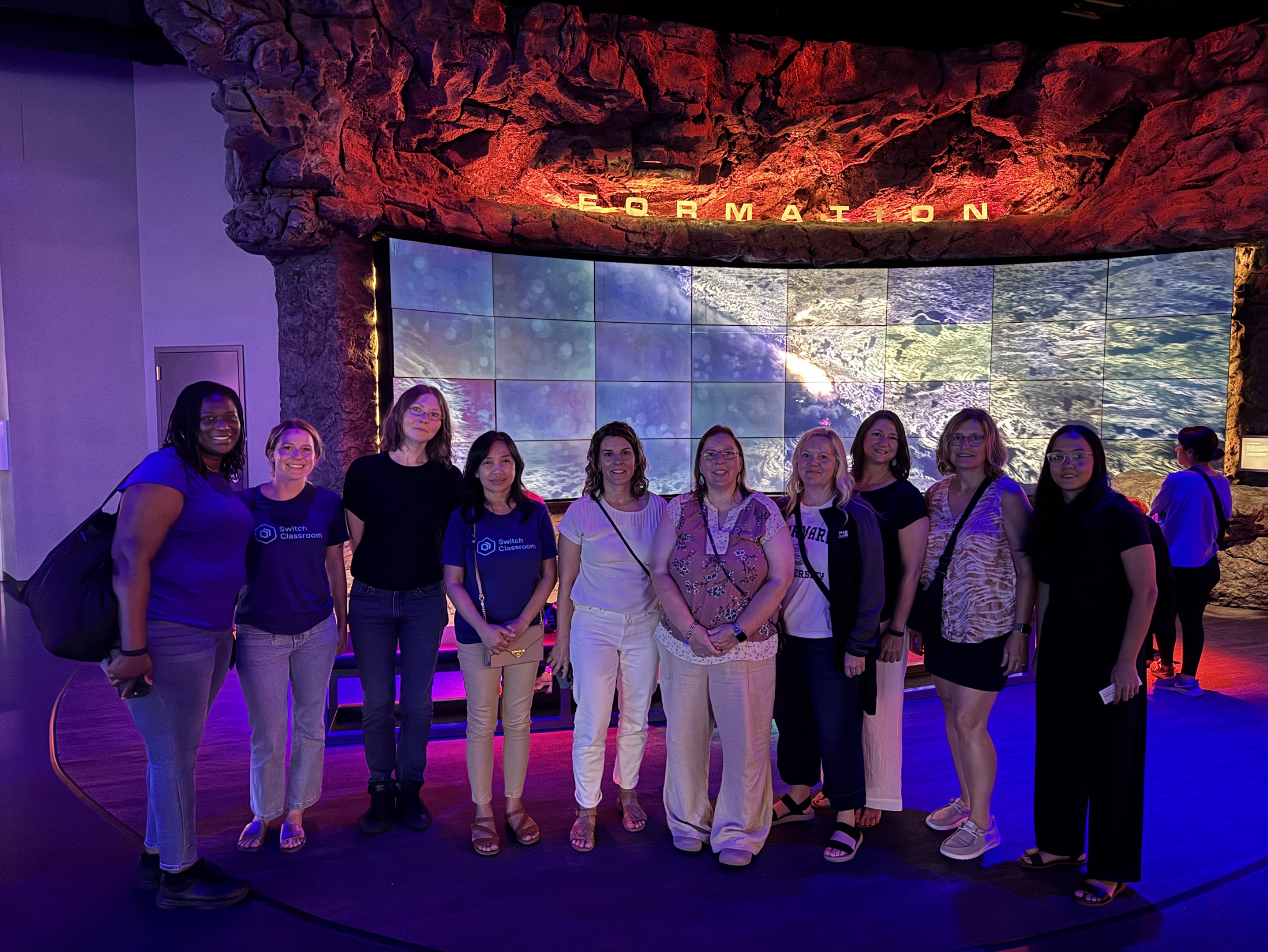 Group of smiling women at an exhibit at the TAC Summer Institute.