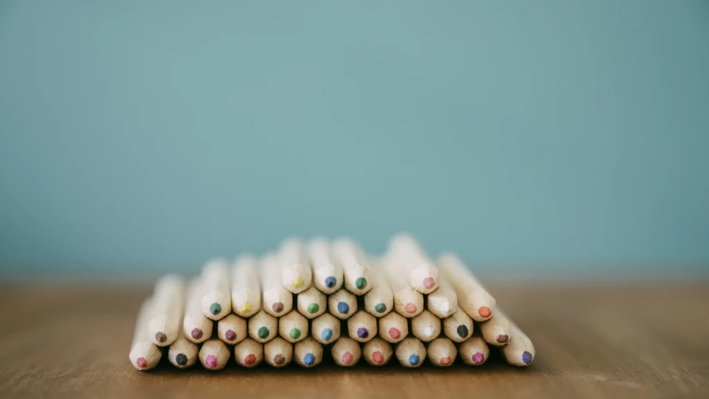 Colored pencils stacked on top of each other with blue background.